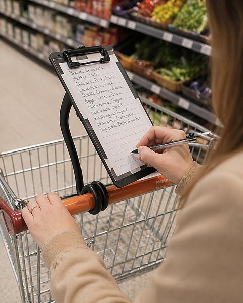 A shopper writing on a list clipped to a Twistaroo on her trolley